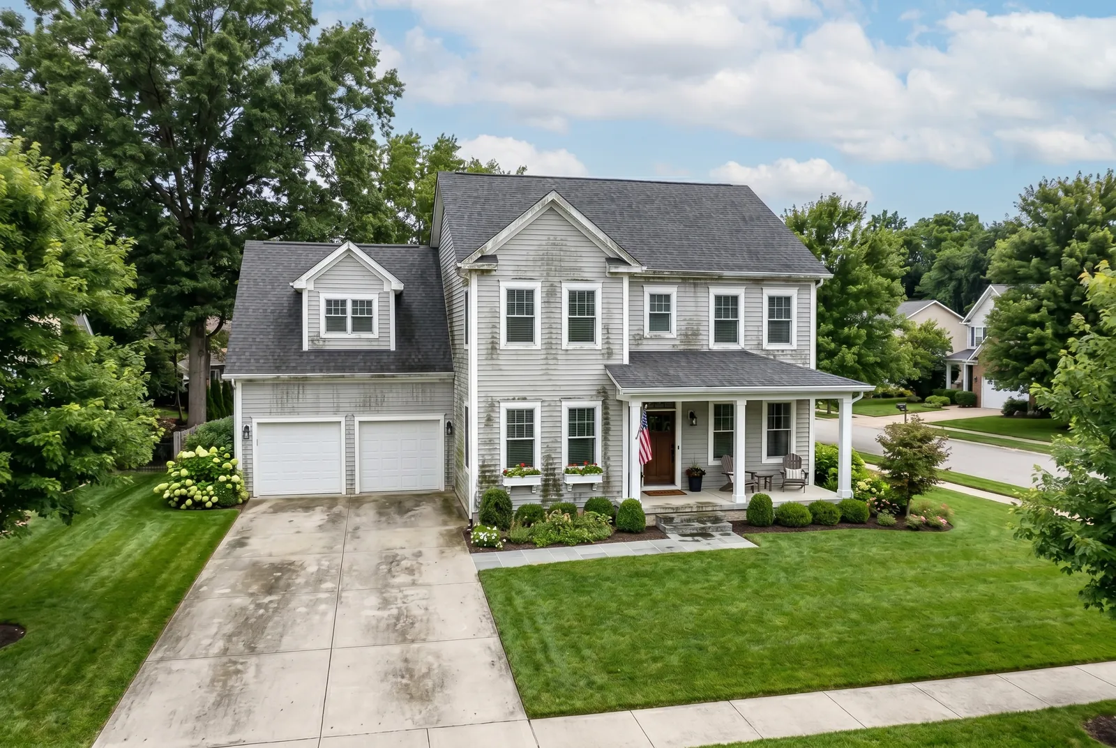 Two-story home before soft washing in St. Matthews, KY, vinyl siding streaked with green and black algae